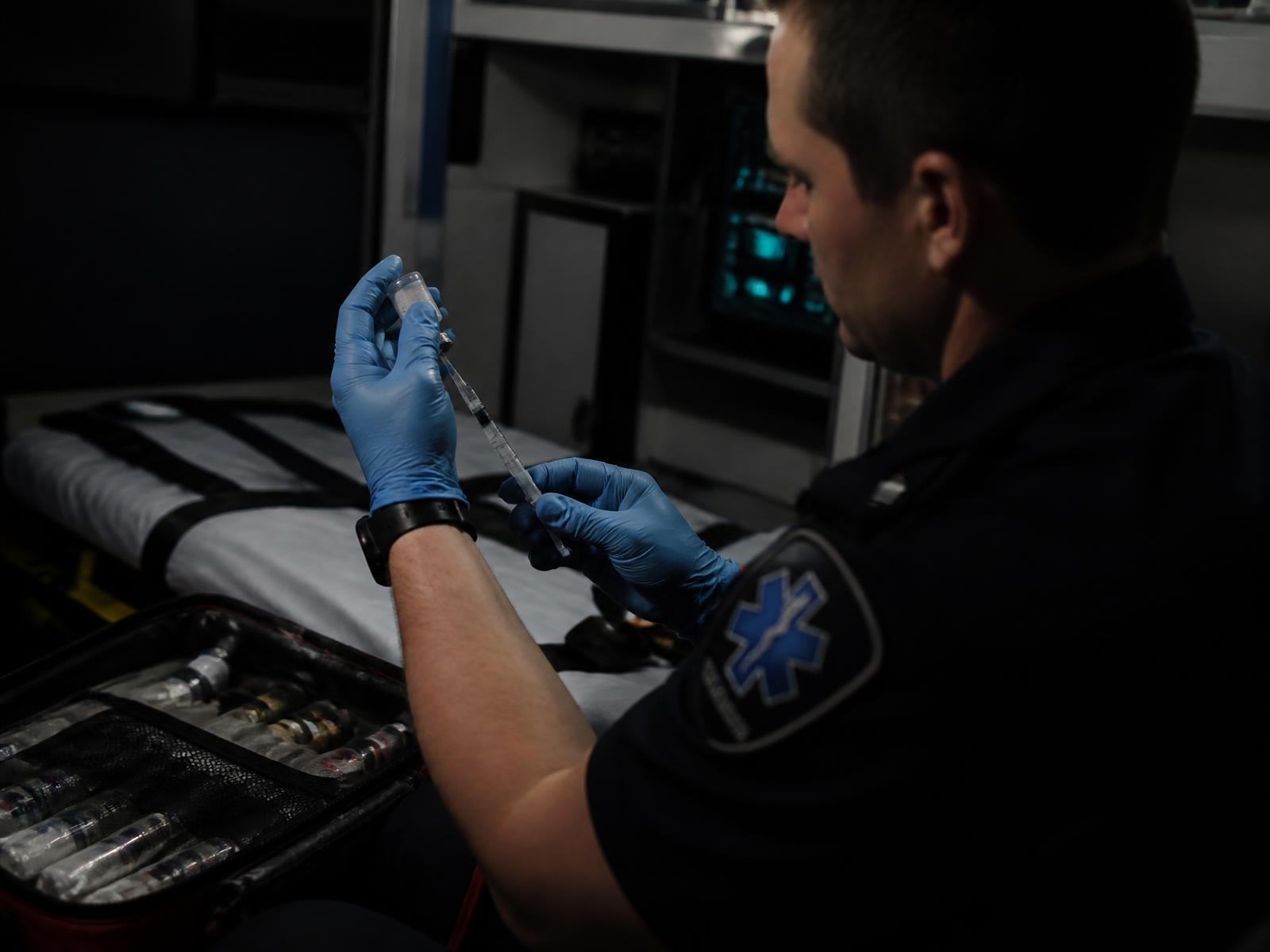 Paramedic drawing medication from a vial into a syringe inside an ambulance